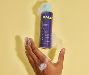 Rally cleanser bottle with suds over reaching hand