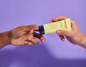 Rally moisturizer tube being passed between 2 hands