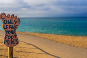 foot shaped sign at beach says leave only your footprints